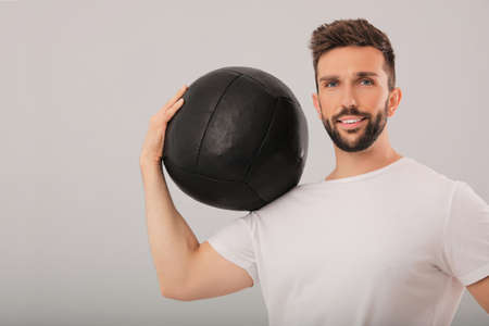 Athletic man with medicine ball on light gray backgroundの写真素材