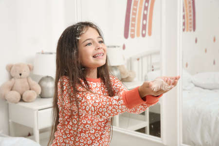 Cute little girl in pajamas playing with feathers at home. Happy childhoodの写真素材
