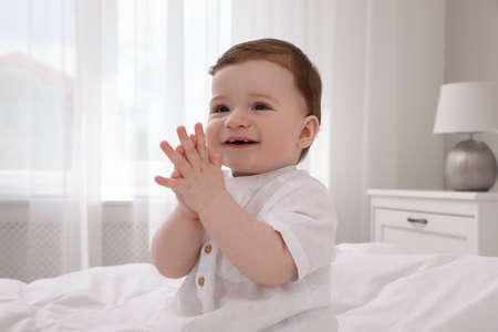 Happy baby boy on bed at homeの写真素材