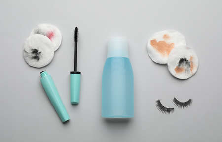Dirty cotton pads, eyelashes, mascara and makeup removal product on light gray background, flat layの写真素材