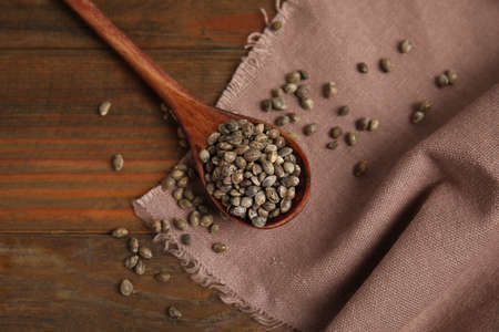 Spoon with organic hemp seeds on wooden table, flat layの写真素材