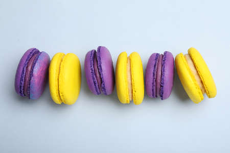 Delicious colorful macarons on light gray background, flat lay