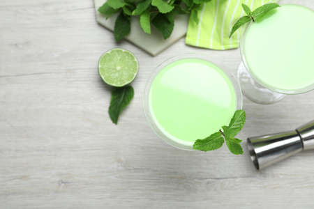 Delicious mint liqueur with green leaves on white wooden table, flat lay. Space for textの写真素材