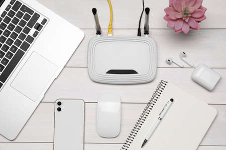 Composition with router, laptop and office stationery on white wooden table, flat layの写真素材