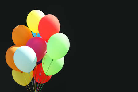 Bunch of colorful balloons on black background. Space for text