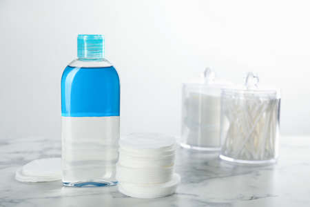 Cotton pads and makeup removal product on white marble tableの写真素材