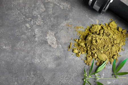 Hemp protein powder, fresh leaves and dumbbell on gray table, flat lay. Space for textの写真素材