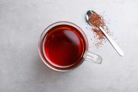 Freshly brewed rooibos tea, scattered dry leaves and spoon on gray table, flat layの写真素材