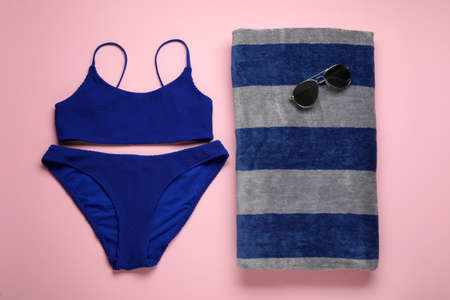 Beach towel, swimsuit and sunglasses on pink background, flat layの写真素材