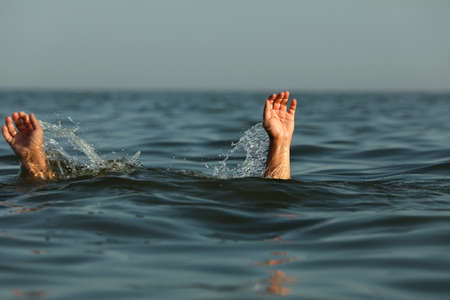 Drowning man reaching for help in seaの写真素材