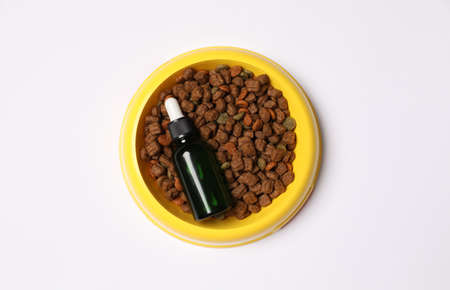 Glass bottle of tincture and dry pet food in bowl on white background, top viewの写真素材