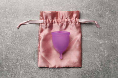 Menstrual cup and cotton bag on gray background, top view. Reusable feminine hygiene productの写真素材