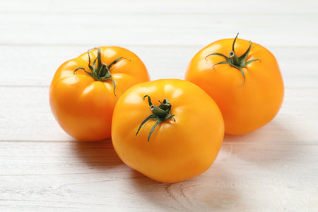 Fresh ripe yellow tomatoes on white wooden tableの写真素材