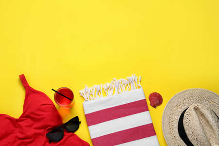 Beach towel, swimsuit, straw hat and sunglasses on yellow background, flat lay. Space for textの写真素材