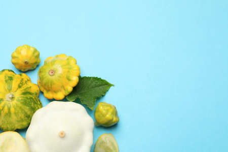 Fresh ripe pattypan squashes on light blue background, flat lay. Space for text