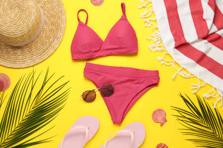 Towel, swimsuit and different beach accessories on yellow background, flat layの写真素材