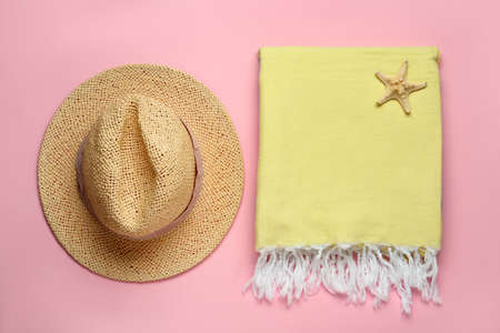 Beach towel and straw hat on pink background, flat layの写真素材