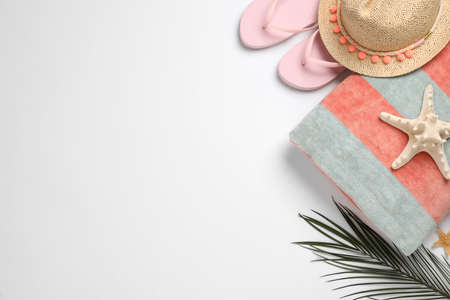 Beach towel, flip flops and hat on white background, flat lay. Space for textの写真素材