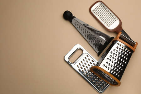 Different modern graters on beige background, flat lay. Space for textの写真素材