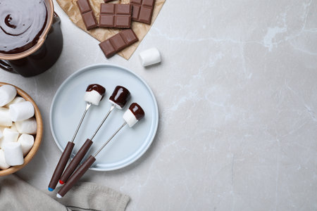 Tasty marshmallows dipped into chocolate on light gray marble table, flat lay. Space for textの写真素材
