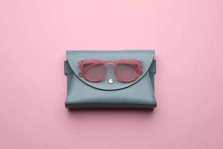Stylish woman's bag and sunglasses on pink background, top view