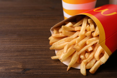 MYKOLAIV, UKRAINE - AUGUST 12, 2021: Big portion of McDonald's French fries on wooden table, closeup. Space for textのeditorial素材