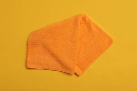 Folded orange beach towel on yellow background, top viewの写真素材