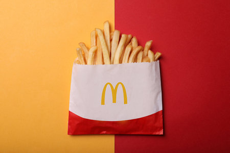 MYKOLAIV, UKRAINE - AUGUST 12, 2021: Small portion of McDonald's French fries on color background,...