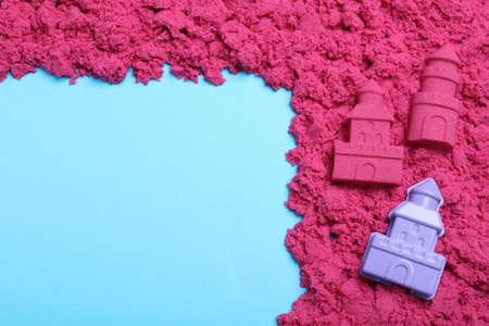Pink kinetic sand and toy on light blue background, flat lay. Space for textの写真素材
