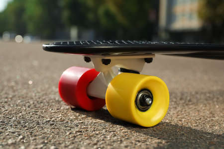 Black skateboard with colorful wheels on asphalt outdoors, closeupの写真素材
