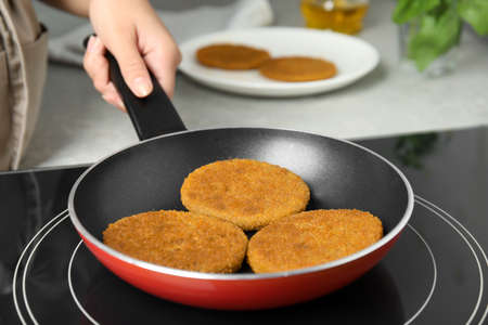 Woman cooking breaded cutlets in frying pan on stove, closeupの写真素材