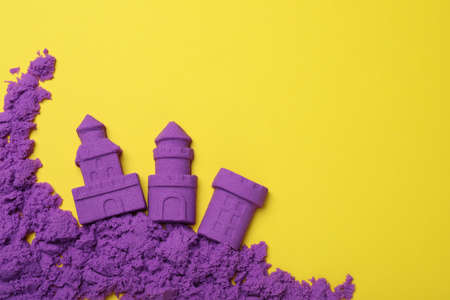 Castles made of kinetic sand on yellow background, flat lay. Space for textの写真素材