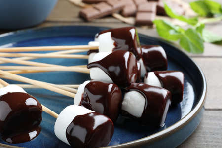 Delicious marshmallows covered with chocolate on plate, closeupの写真素材