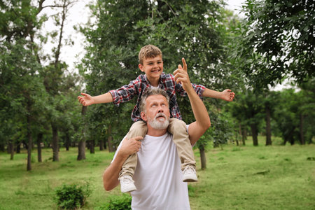 Cute little boy and grandfather spending time together in park
