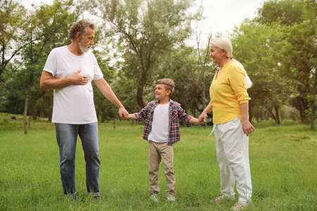 Cute little boy and grandparents spending time together in parkの写真素材