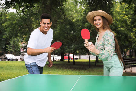 Happy couple playing table tennis in parkの写真素材