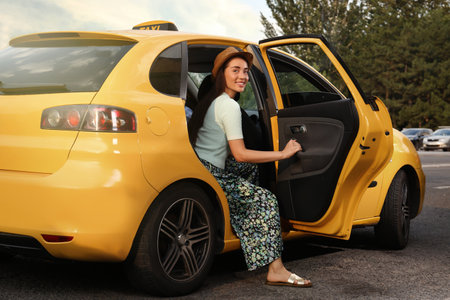 Beautiful young woman getting out of taxi on city street