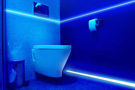 Toilet bowl in public restroom lit with UV blue lightの写真素材