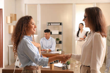 Boss shaking hand with new coworker in officeの写真素材