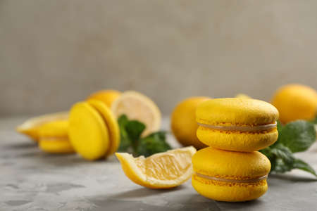 Delicious yellow macarons and lemon on light gray table. Space for textの写真素材