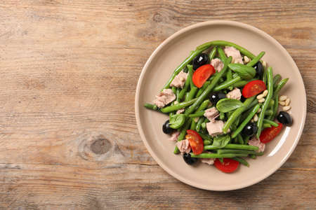 Plate of tasty salad with green beans on wooden table, top view. Space for textの写真素材