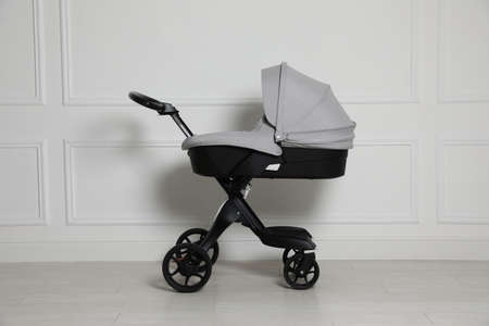 Baby carriage. Modern pram near white wall