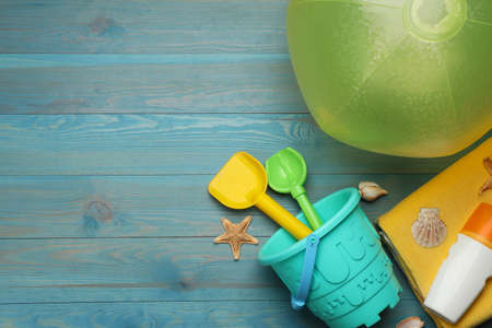 Flat lay composition with beach ball and sand toys on light blue wooden background. Space for textの写真素材