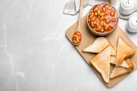 Toasts and delicious canned beans on white table, flat lay. Space for textの写真素材