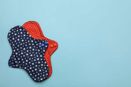 Reusable cloth menstrual pads on light blue background, flat lay. Space for textの写真素材