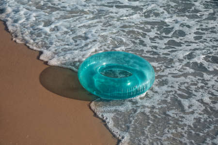Bright inflatable ring on sandy beach near seaの写真素材