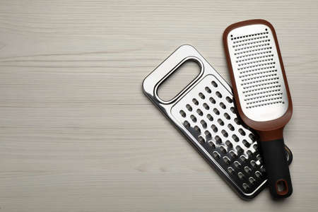 Modern graters on white wooden table, flat lay. Space for textの写真素材