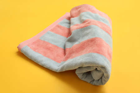Rolled striped beach towel on yellow backgroundの写真素材