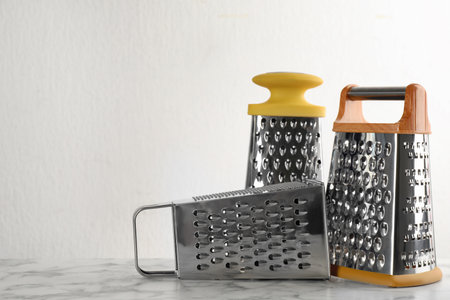 Different modern graters on white marble table. Space for textの写真素材