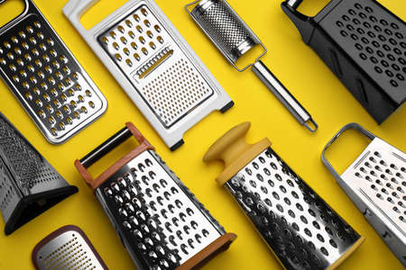 Different modern graters on yellow background, flat layの写真素材